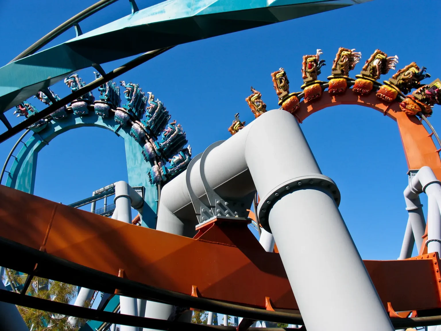 Double loop roller coaster with carriages launching at high speed on colorful tracks against the blue sky
