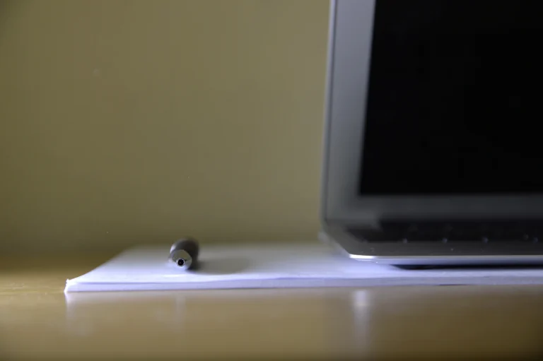 Laptop aperto su una scrivania con un blocco di fogli e una penna appoggiata sopra.